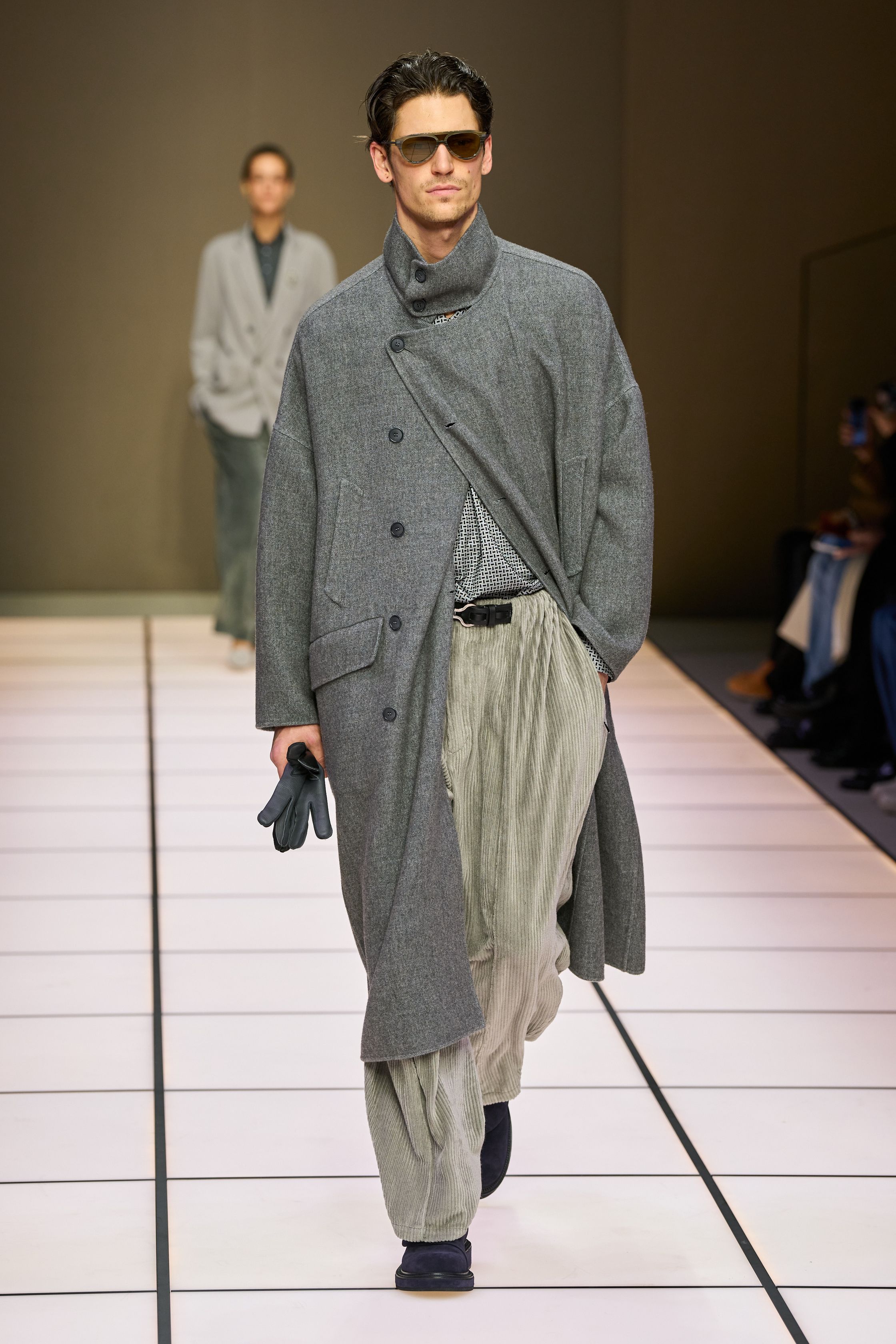 Giorgio Armani 26FW 男装回归品牌最本质的语言：流动、克制与永恒。柔软大衣、宽松长裤、针织与轻结构西装在灰、驼、米与墨绿中缓慢展开，强调身体与面料之间的自然关系。系列几乎不依赖任何戏剧化装饰，却通过比例、步伐与质感建立权威感，是对“真正优雅无需证明”的再次确认，也是一种对快节奏时尚的温和抵抗-顽石频道趋势研究